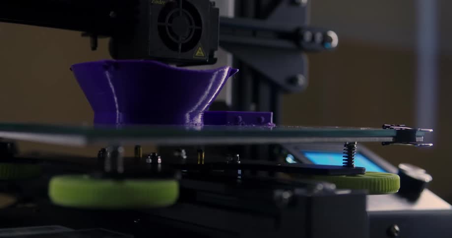 A three dimensional printer creates a purple bowl shaped object