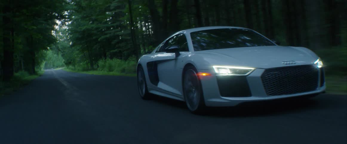 A sports car drives on a road in the woods