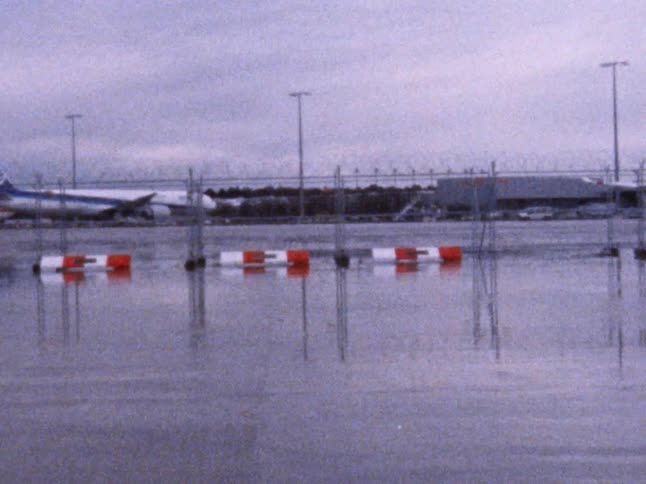 Four young white males skateboard near a fence at an airport