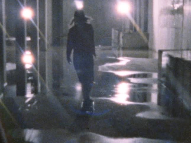 A teenager skateboards through a puddle at night