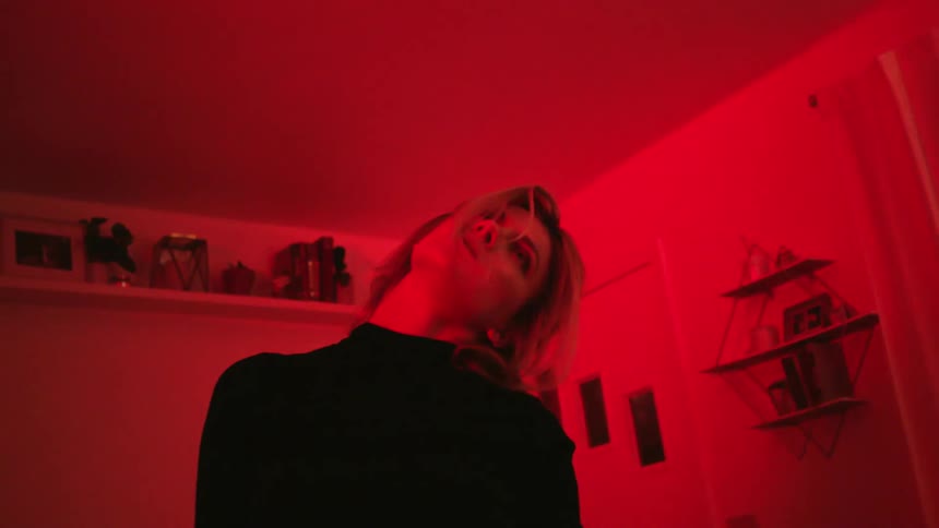 A woman stretches her neck as lights change color in her living room