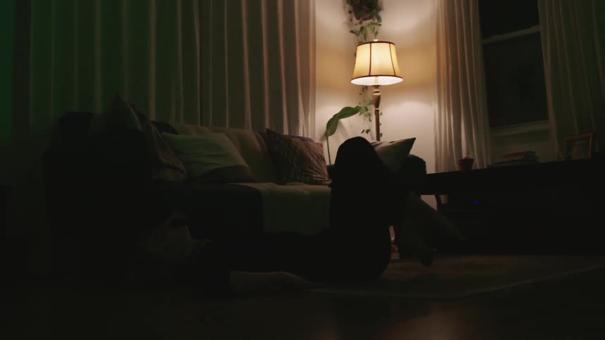 A woman stretches her legs on the floor while watching television