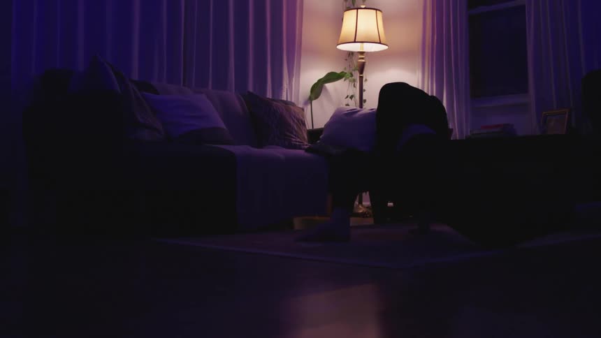Woman dances in living room while colored lights tint the area various colors