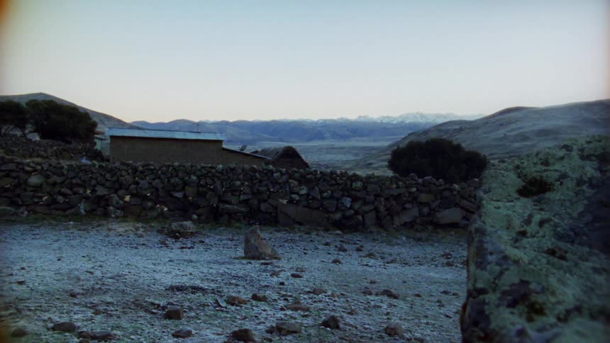 A small building sits near a stone wall in a rural area