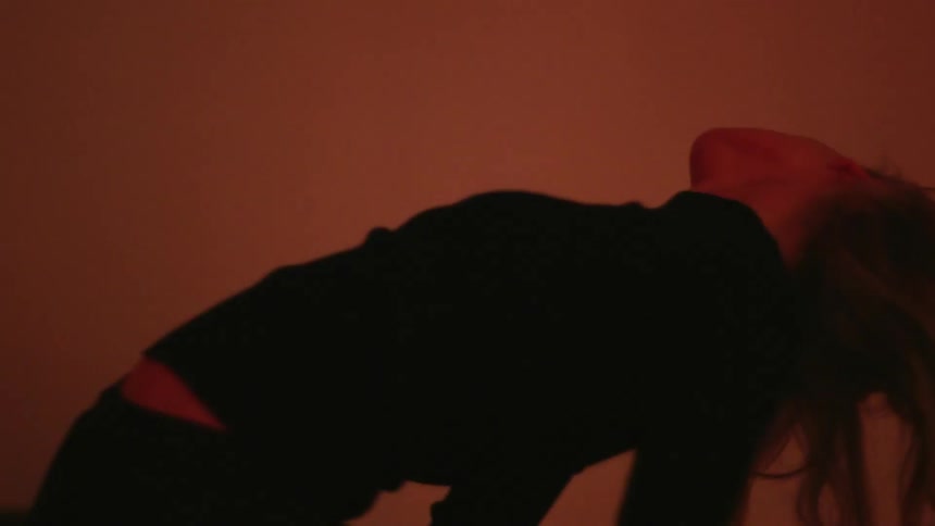 A female leans back and dances while lights flash