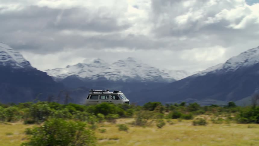 A van is driving off road by the mountains