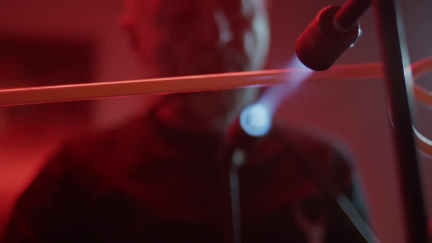 An elderly white man heats up a tube with a torch flame
