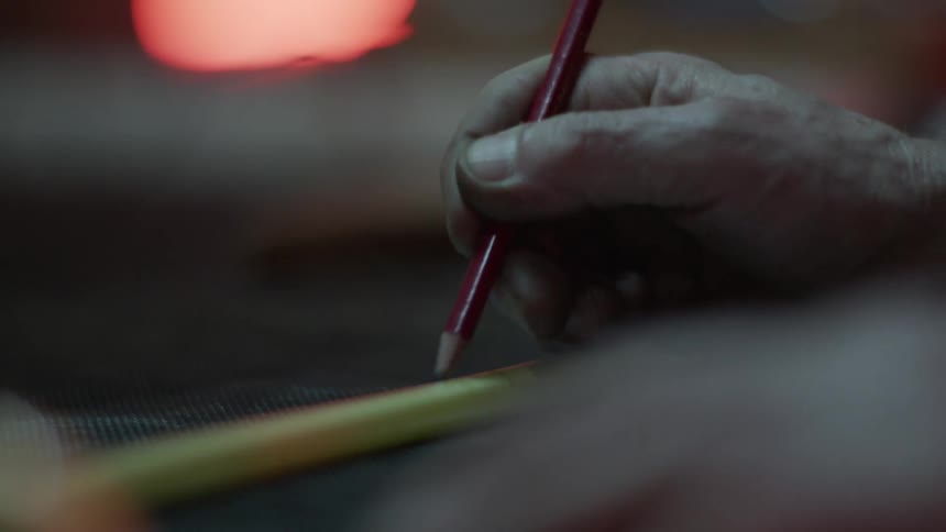 A white man marks a yellow tube with a red pencil