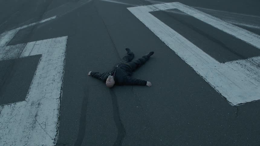 Person laying on the ground in the middle of the road