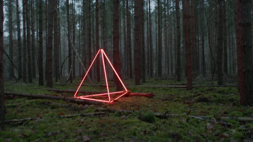 A lighted up 3d triangle sits in a forest