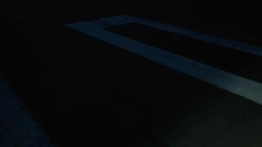 A spotlight illuminates the shadow of a person on a road