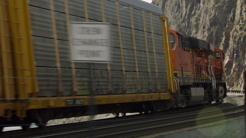 Freight train travels along train tracks near a lake in a dynamic and rapidly evolving shot great to show America hard at work