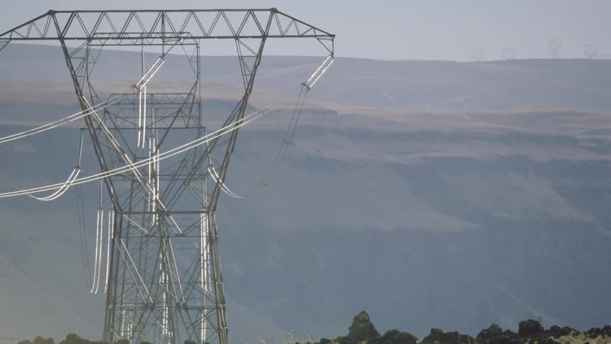 Power lines in transmission towers across deserted mountains and mesas