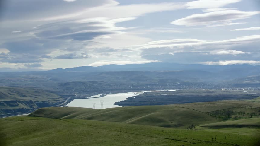 High above the Columbia River Gorge in rural Washington with green meadow grass and lenticular clouds in the vast afternoon sky