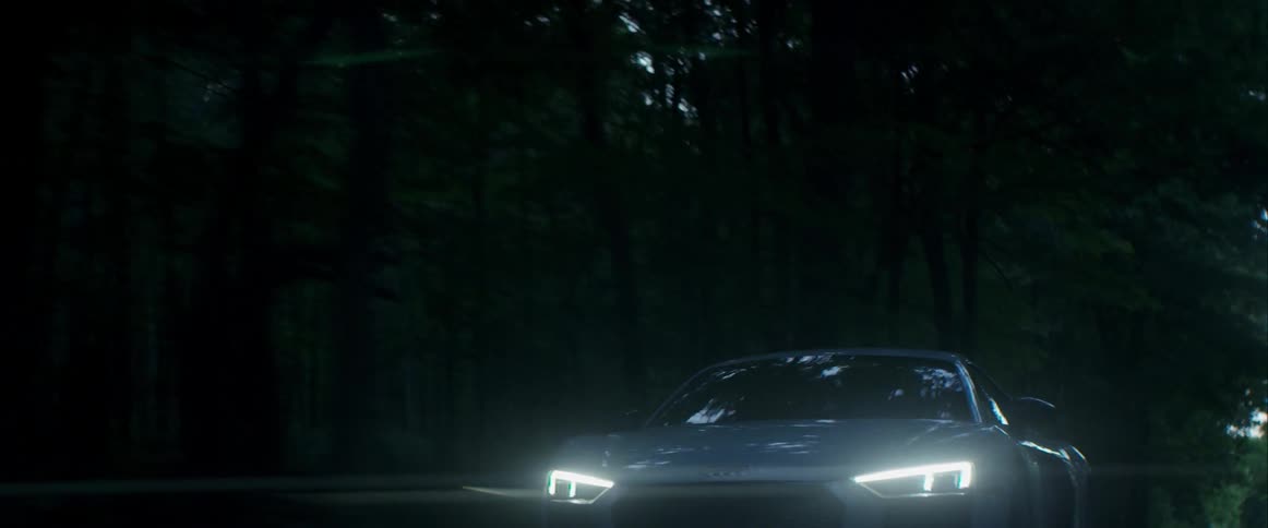 A white car drives through a forest