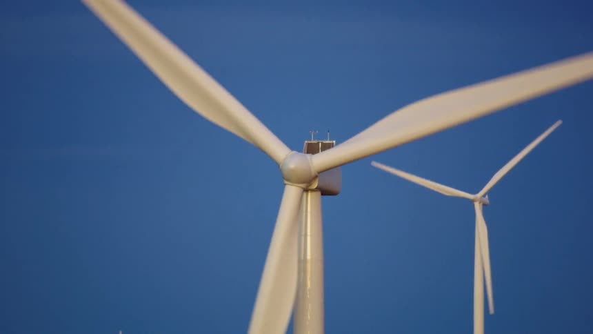 Beautiful blue hour shot of three wind mills rotating with golden sunset light illuminating the windmills themselves