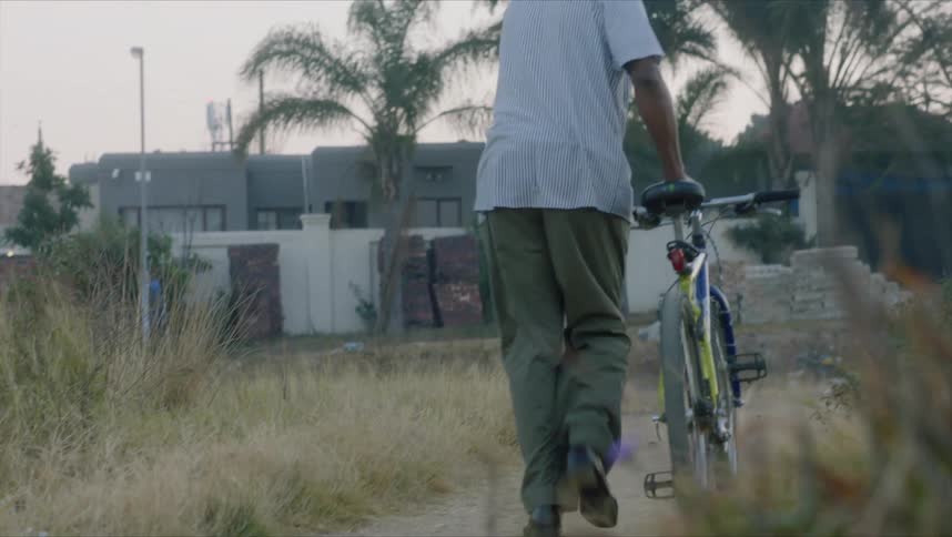 A man walks his bike down a pathway