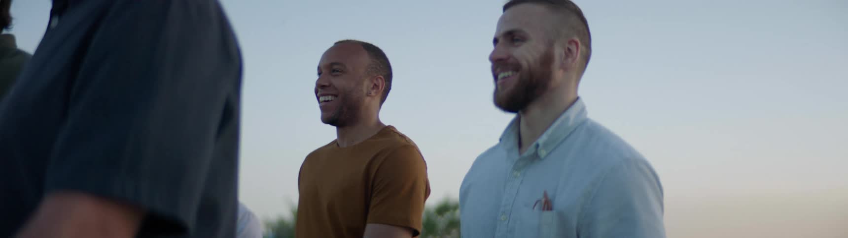 A group of men laugh and talk while walking outdoors