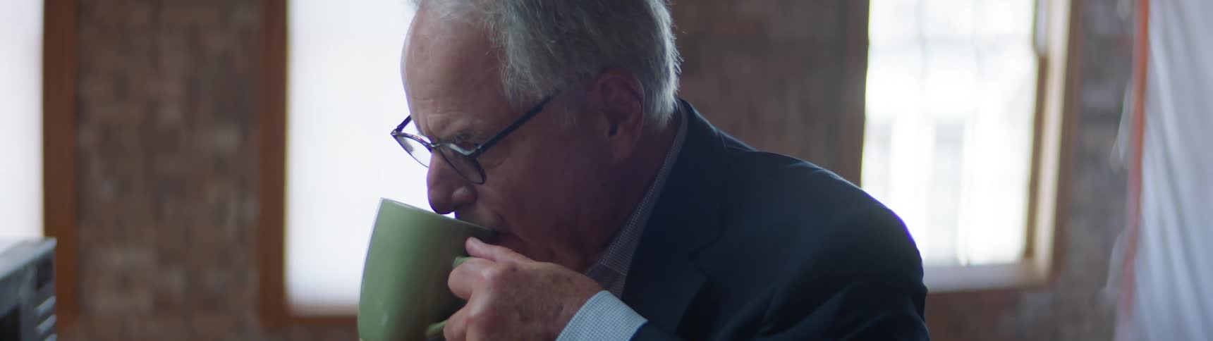 An elderly man drinks a cup of coffee