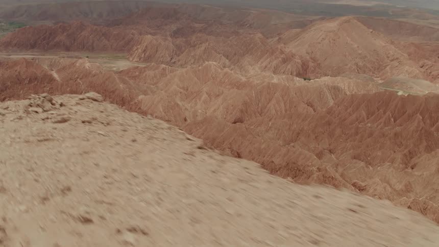 Dirt and rocks litter the edge of high ground that gives way to canyons and mountains down below