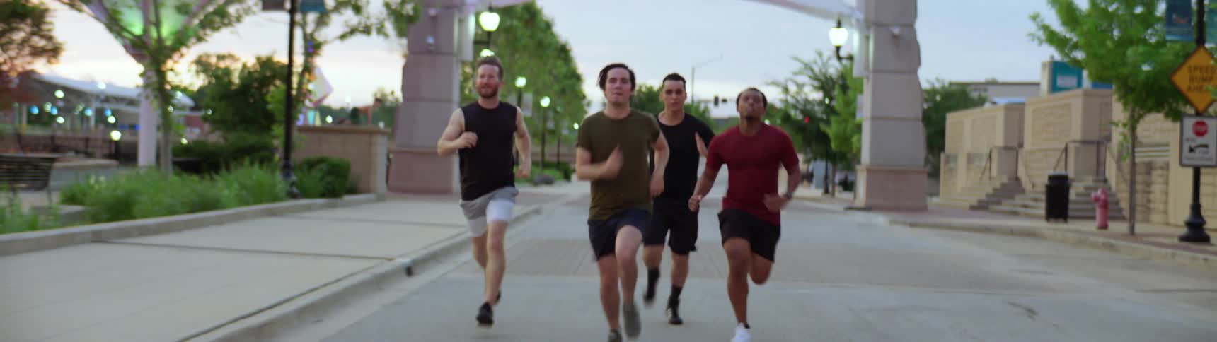 Four men run together on a road