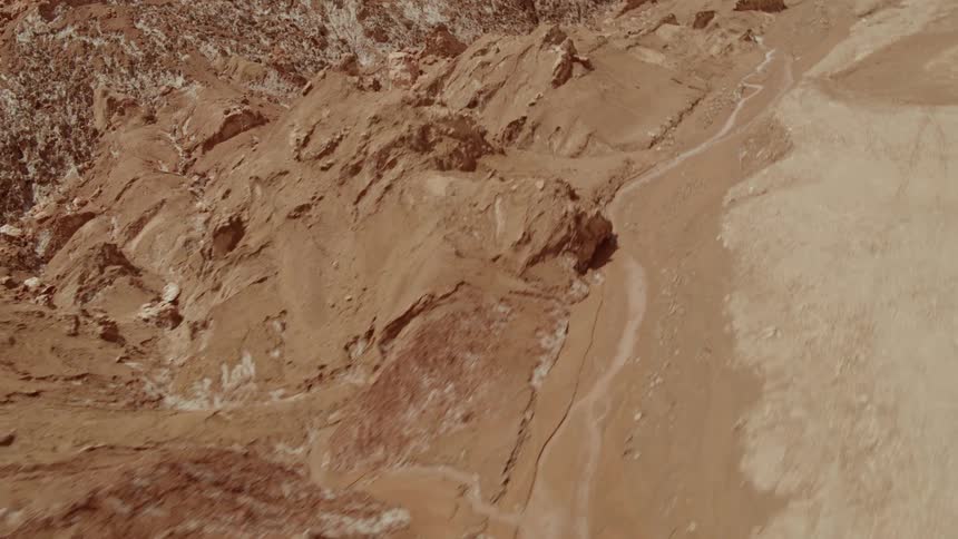 Small hills and a mountain range covered in brown soil