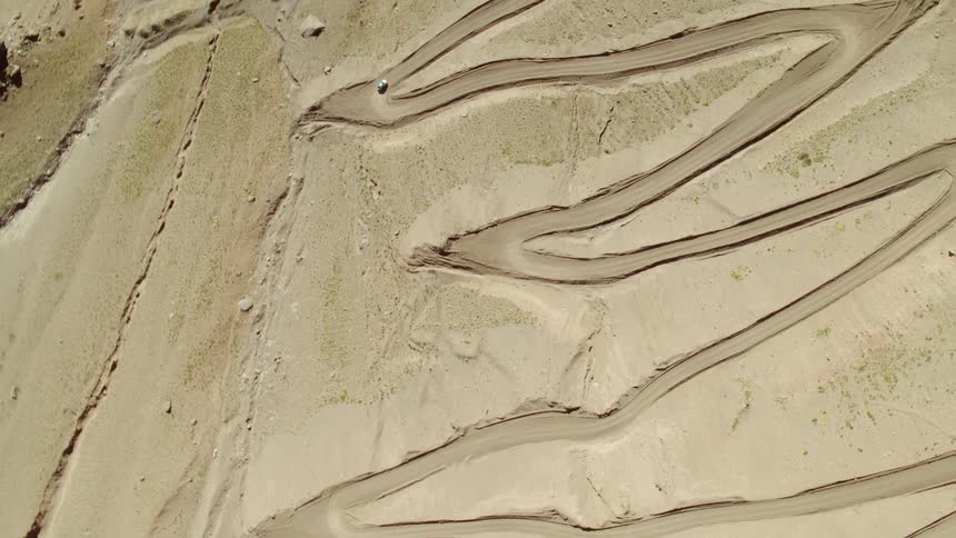A car drives along a snaky road in the desert