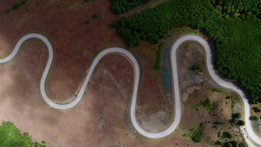 A car takes a winding road through a large patch of open ground