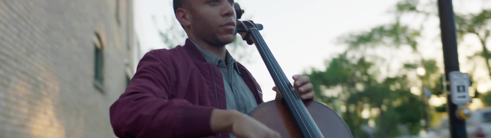 A man playing a cello on a street corner