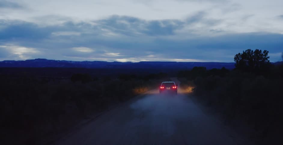 A car driving down a dirt road at night