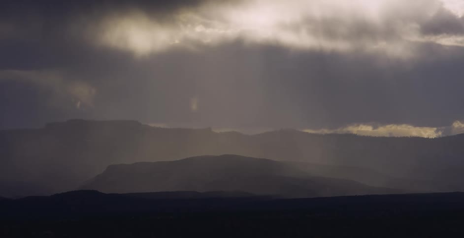 Dark clouds hover over a mountain range and a plain