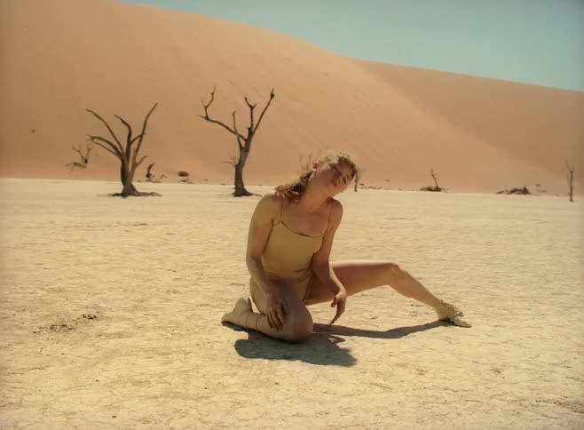 A teenager dances in a desert