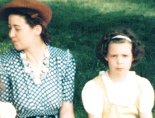 A daughter mugs for the camera and drinks a soda while sitting next to her mother