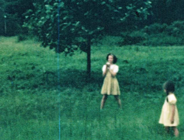 A man playing catch in a field with a baseball with his two daughters and son