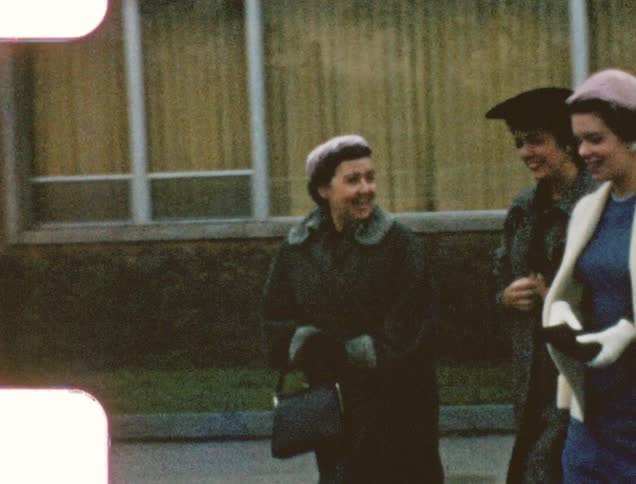 Vintage film of a group of women wearing coats walking on a parking lot