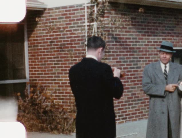 A man stands with a camera taking a picture of a man and woman