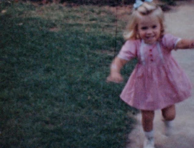 Sisters wearing pink dresses play with a ball on the backyard