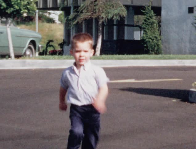 A little white boy runs across a stretch of pavement