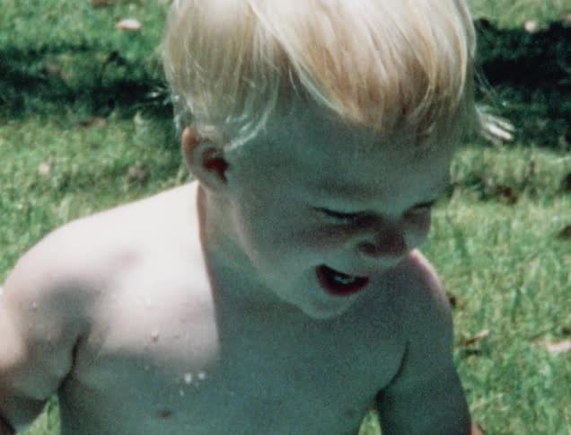 Two young white boys laugh while playing in a wading pool