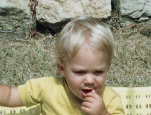 A little boy sits outside and swings