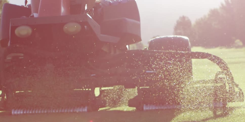 The riding mower is trimming the grass