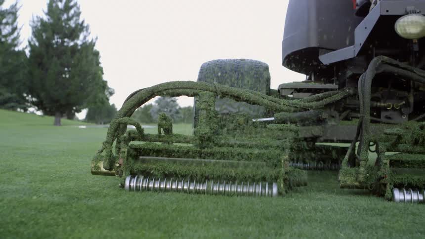 A man rides a large mower over grass