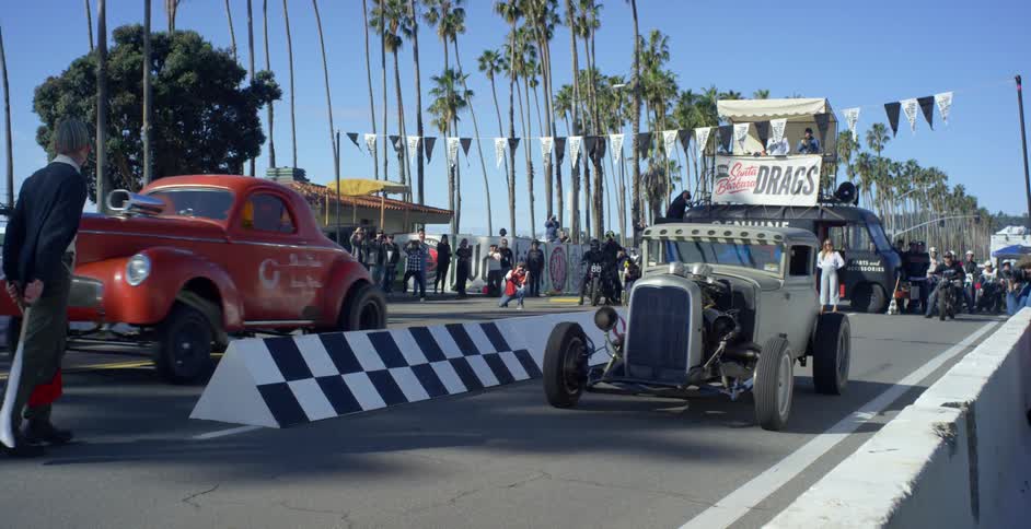 Two vehicles race on a drag strip surrounded by spectators