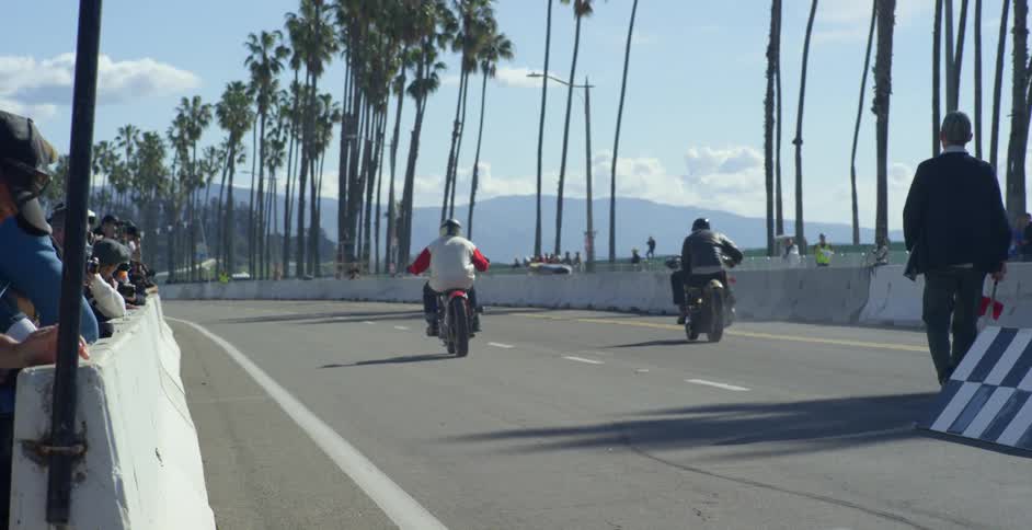 Motorcycles racing down a race track in slow motion