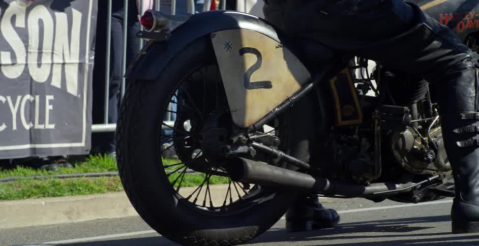 A man sits on a motorcycle as a crowd waits for a race to start
