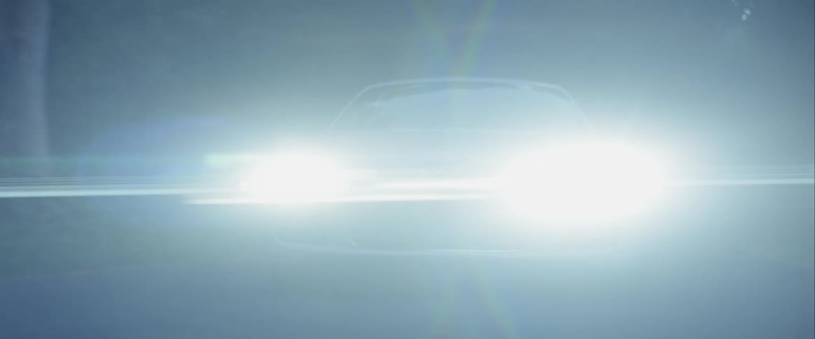 A car drives down a darkened road