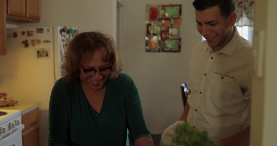 Man and woman smile and talk while washing dishes in kitchen