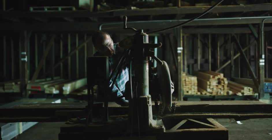 A worker cuts wood with a large saw