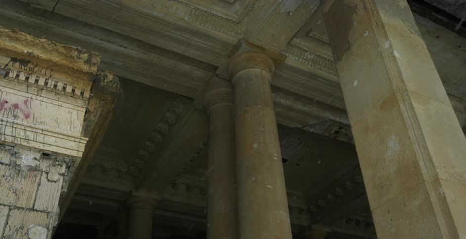 Snow flakes falling around the stone support pillars of old architecture