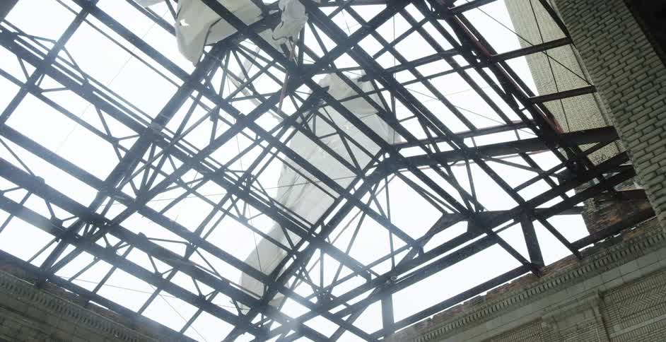 Pieces of tarp flap in the wind on an open roof allowing snow to fall in